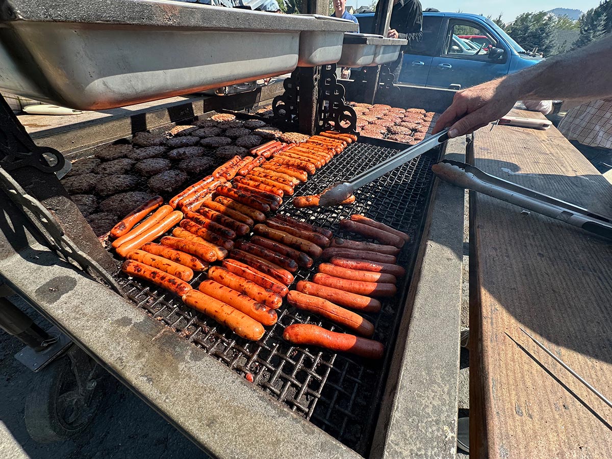 Man flipping hotdogs with tongs